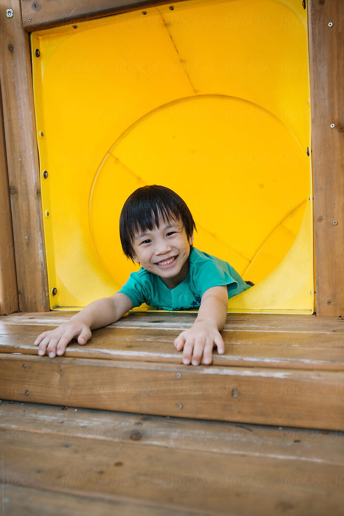 A young kid is all smiles because he is about to go down the slide tunnel