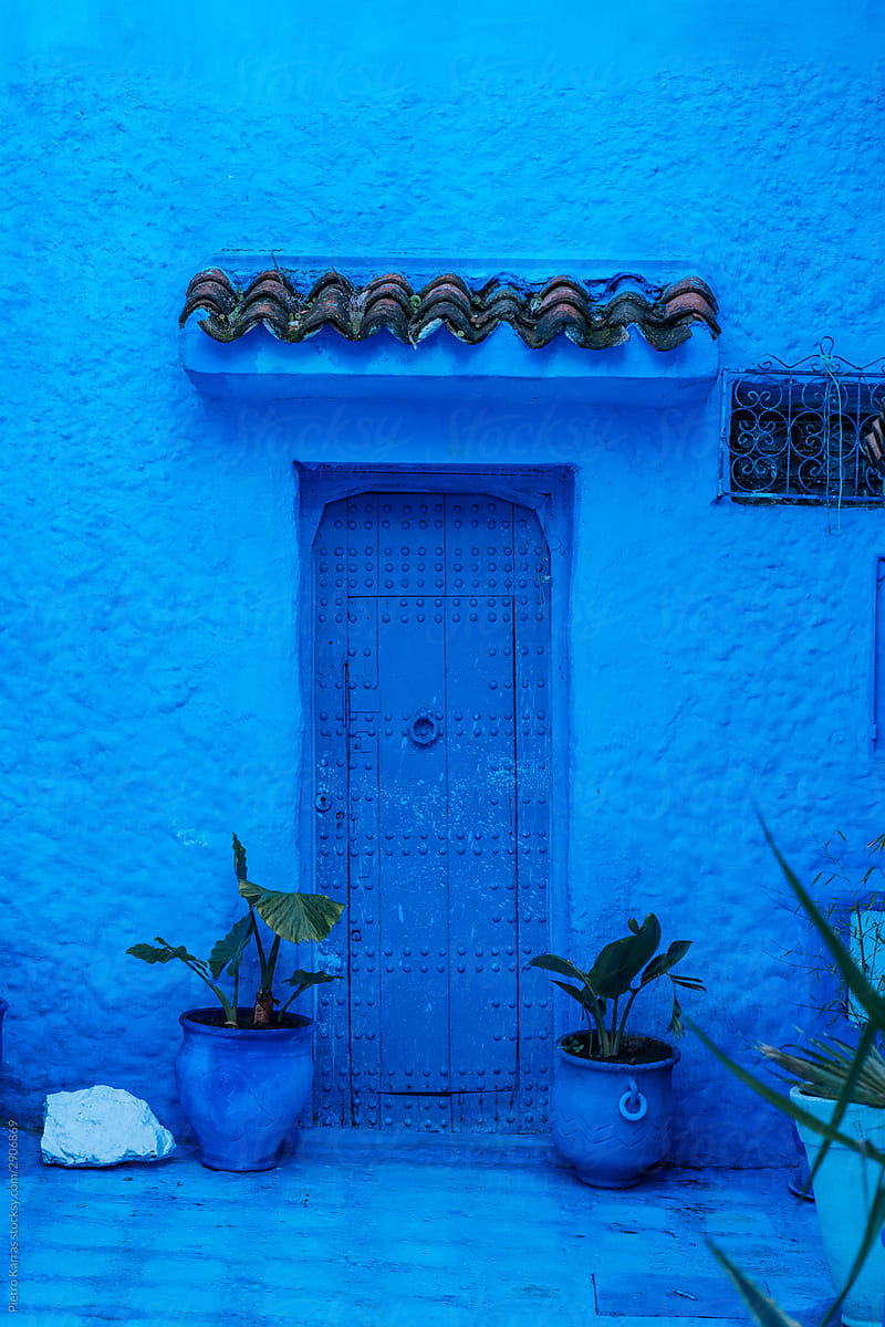 Wooden door with geometric visor over in blue color