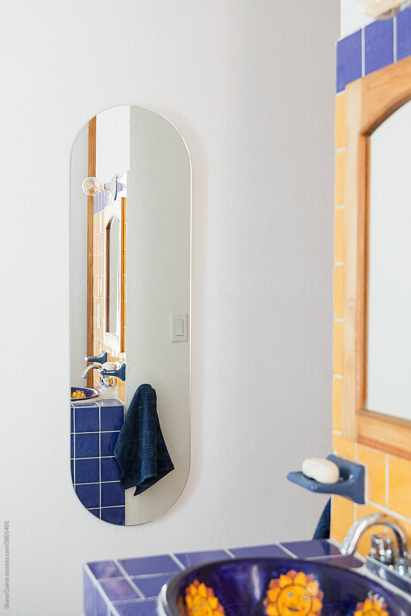 An oval mirror on the white wall next to a bathroom