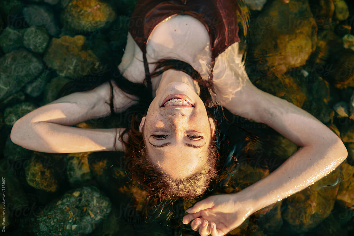 Sea summer portrait of teenage happy freckled girl lying in the water
