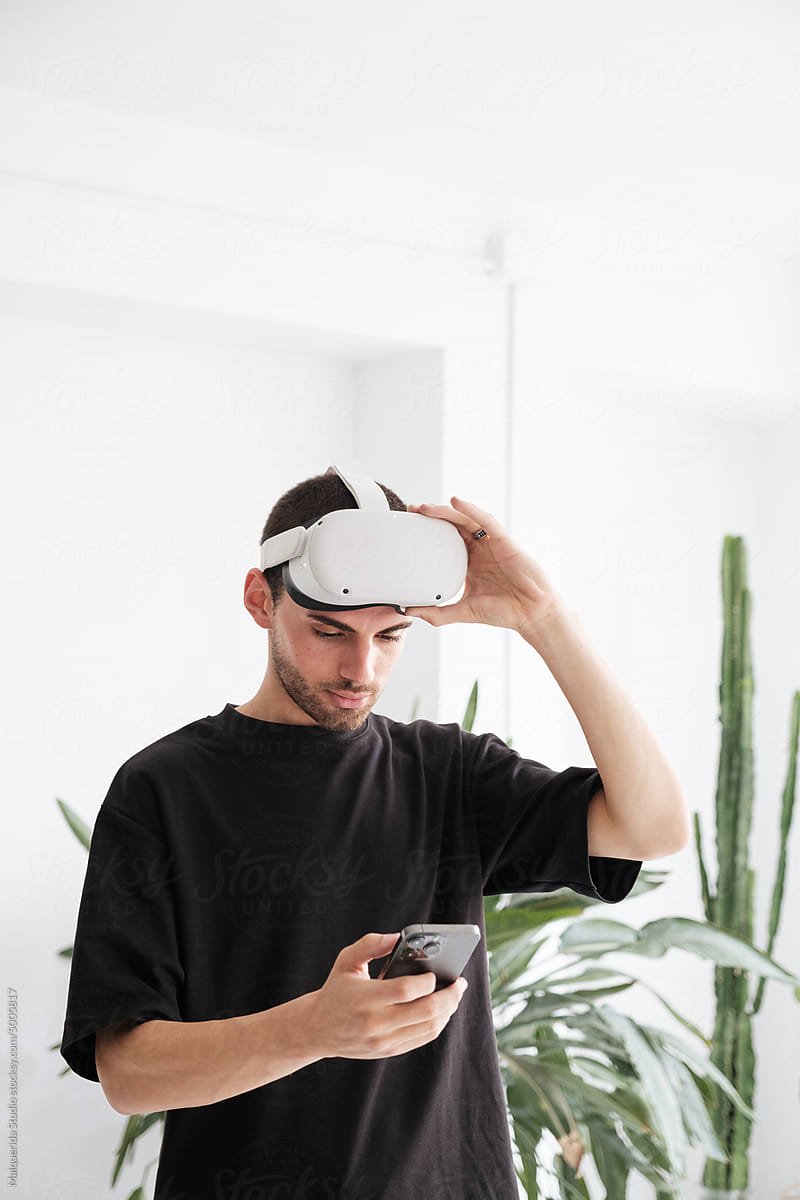 Young man browsing phone while using VR glasses