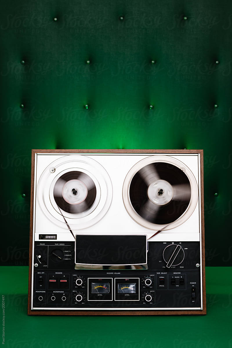 Vintage reel-to-reel tape player/ recorder on green background