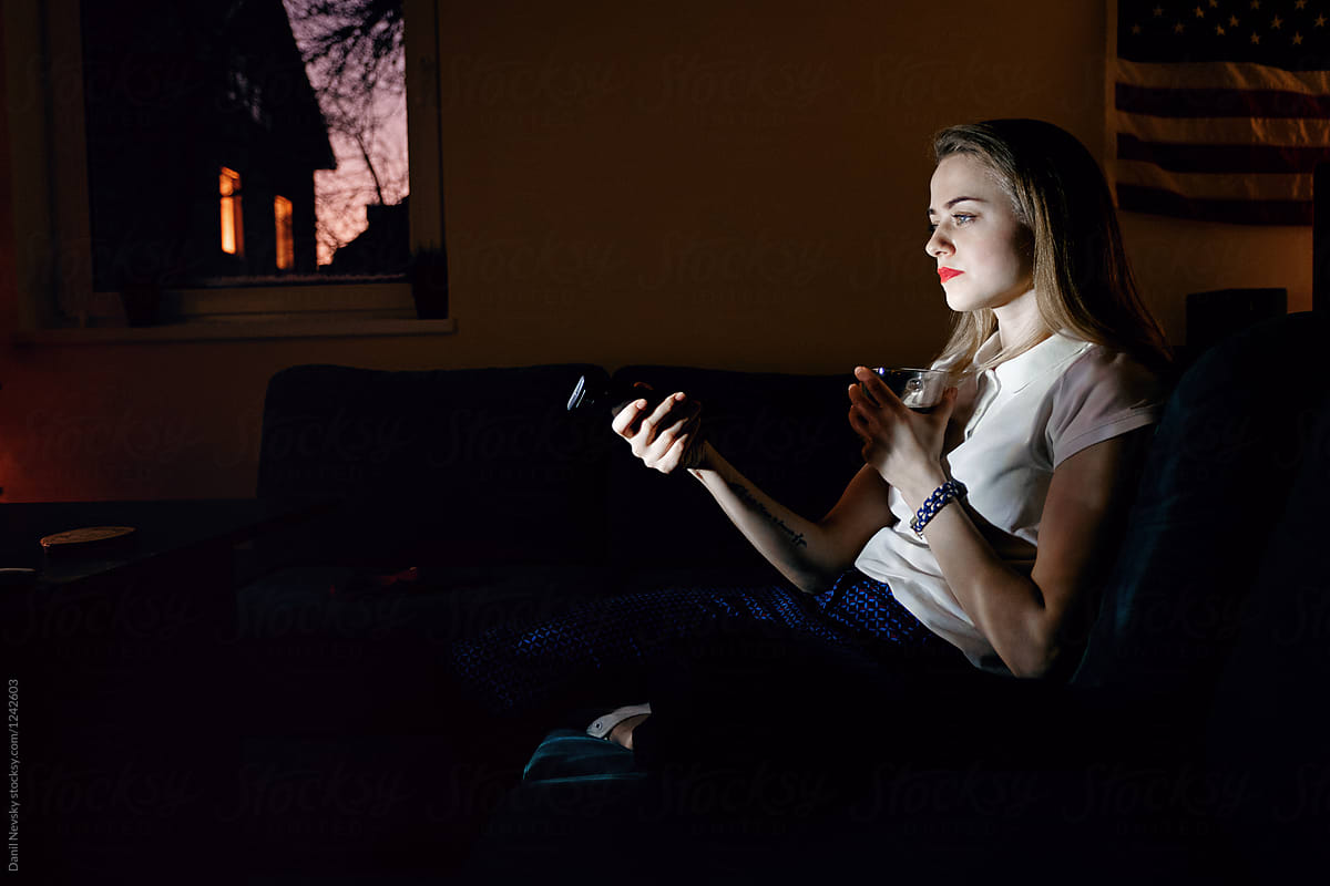 Girl with mug switching channels in darkness