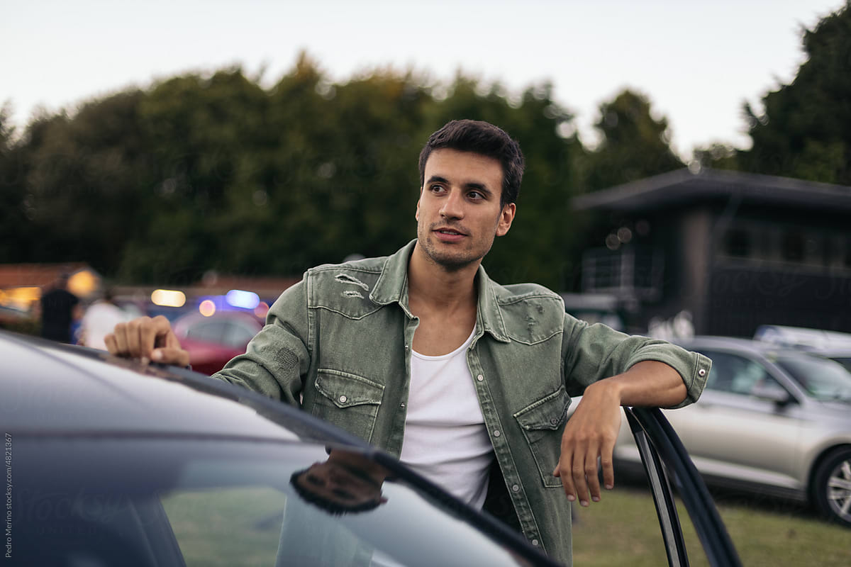 Portrait of young man leaning on car at an outdoor drive-in cinema