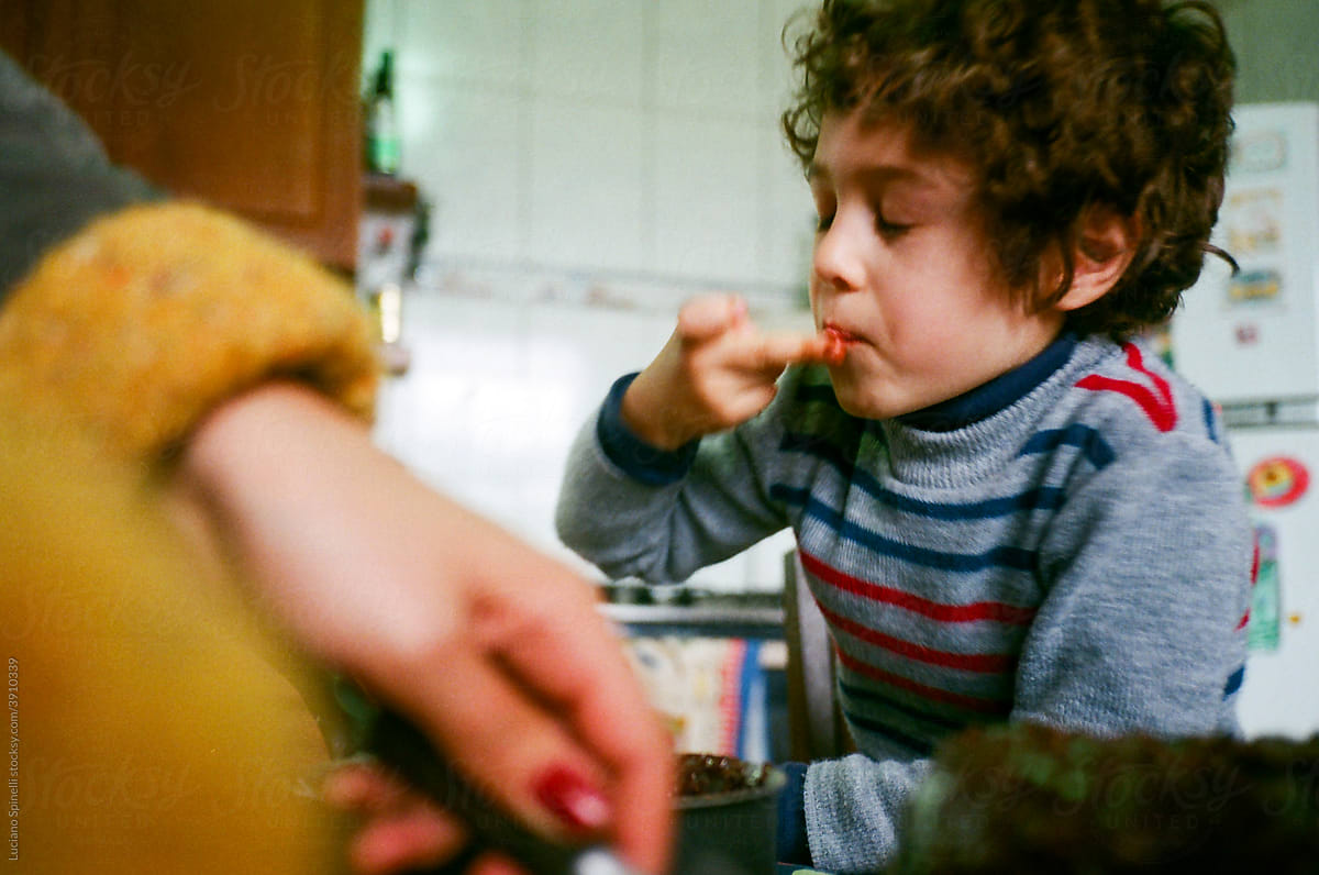 Boy trying food and his mother\'s hand in front of the camera