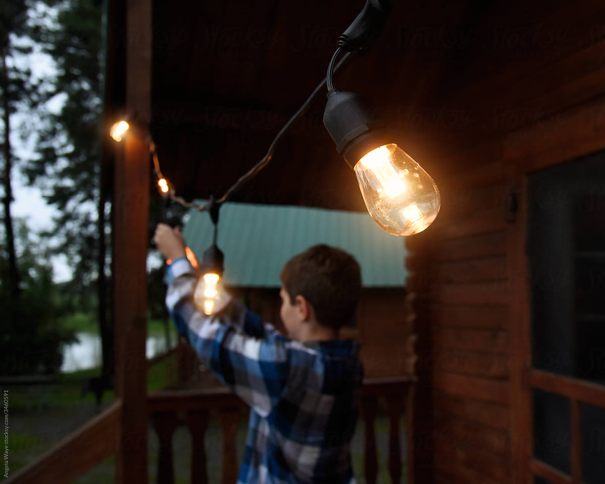 Child Hanging Up Lights Outside of Cabin
