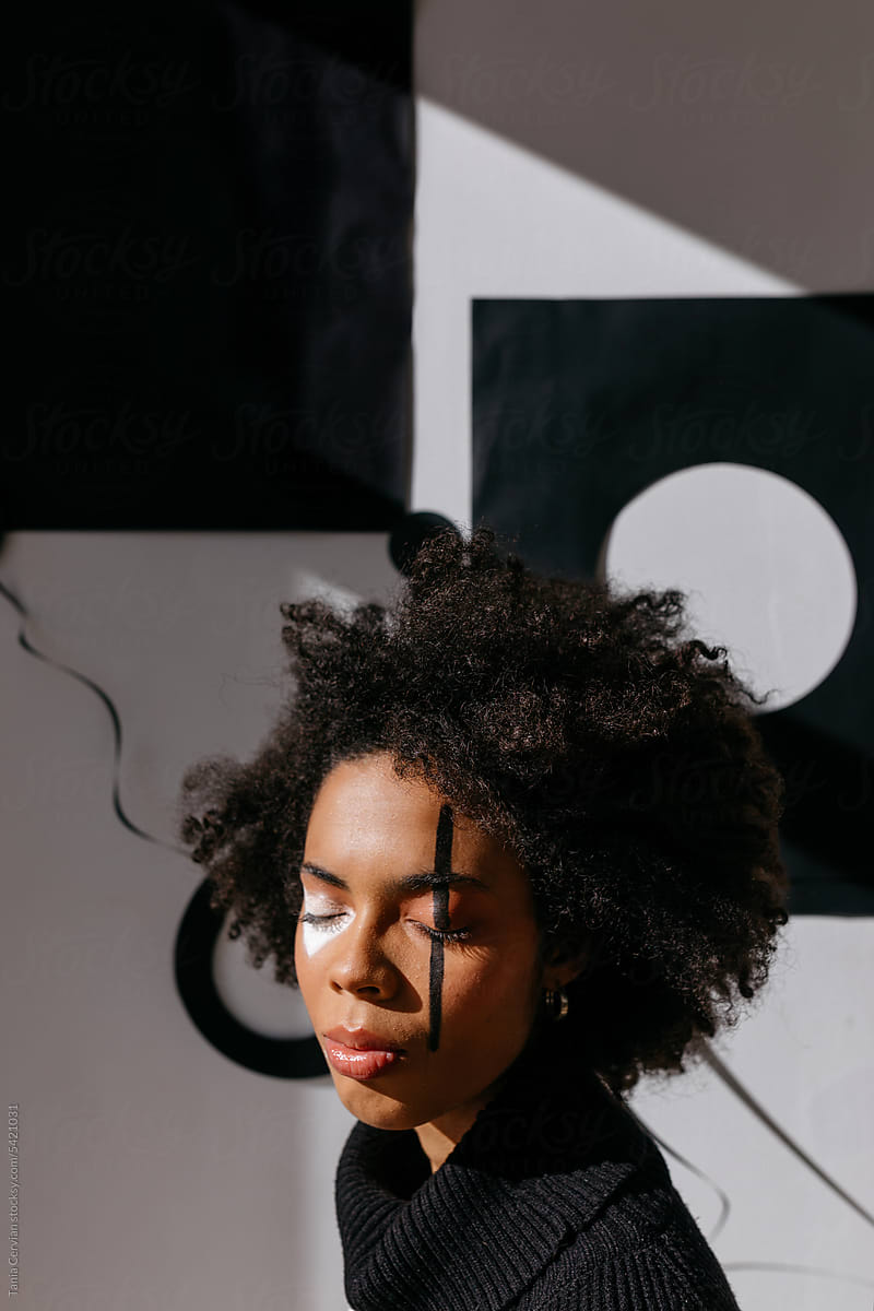 Calm black woman with painted face in sunlight