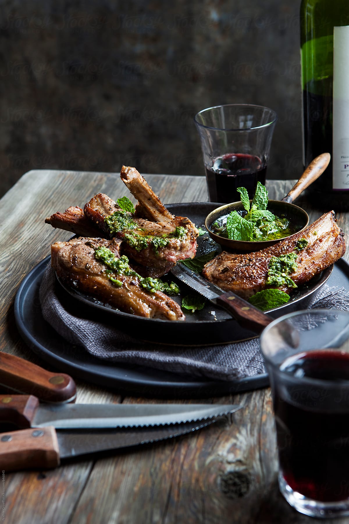 Meat lamb chops with chimichurri sauce and glasses of red wine