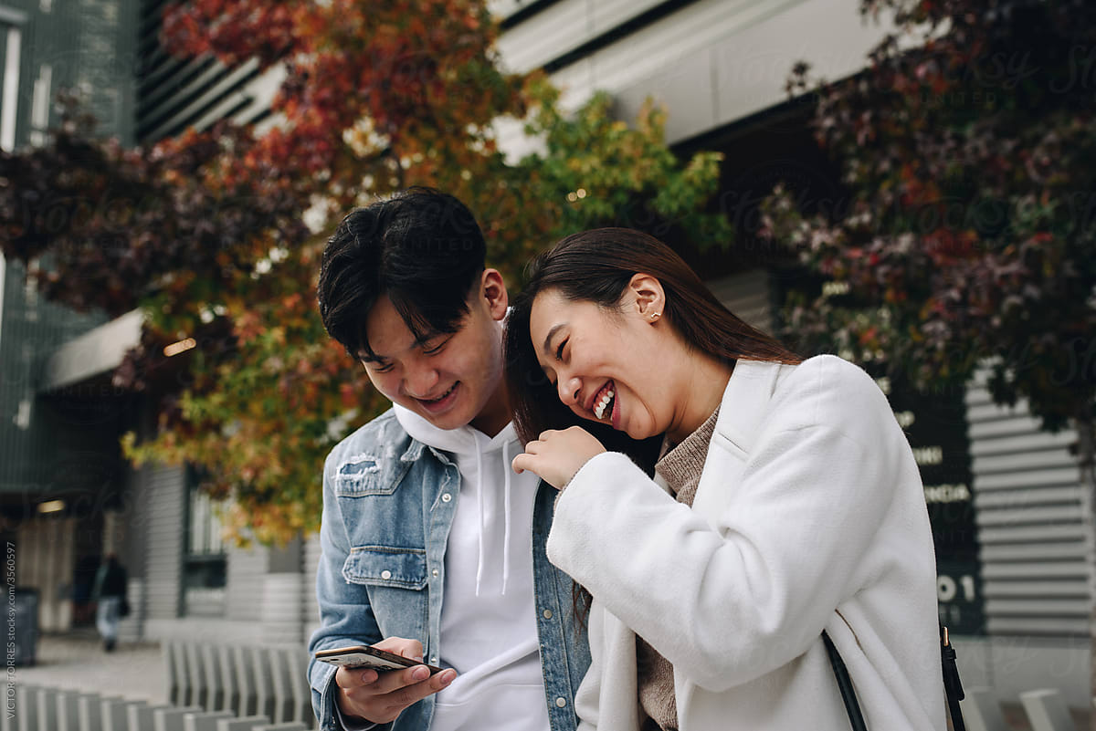 Chinese young couple laughing while looking at the phone