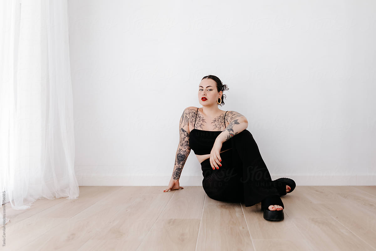 Stylish tattooed woman sitting in studio