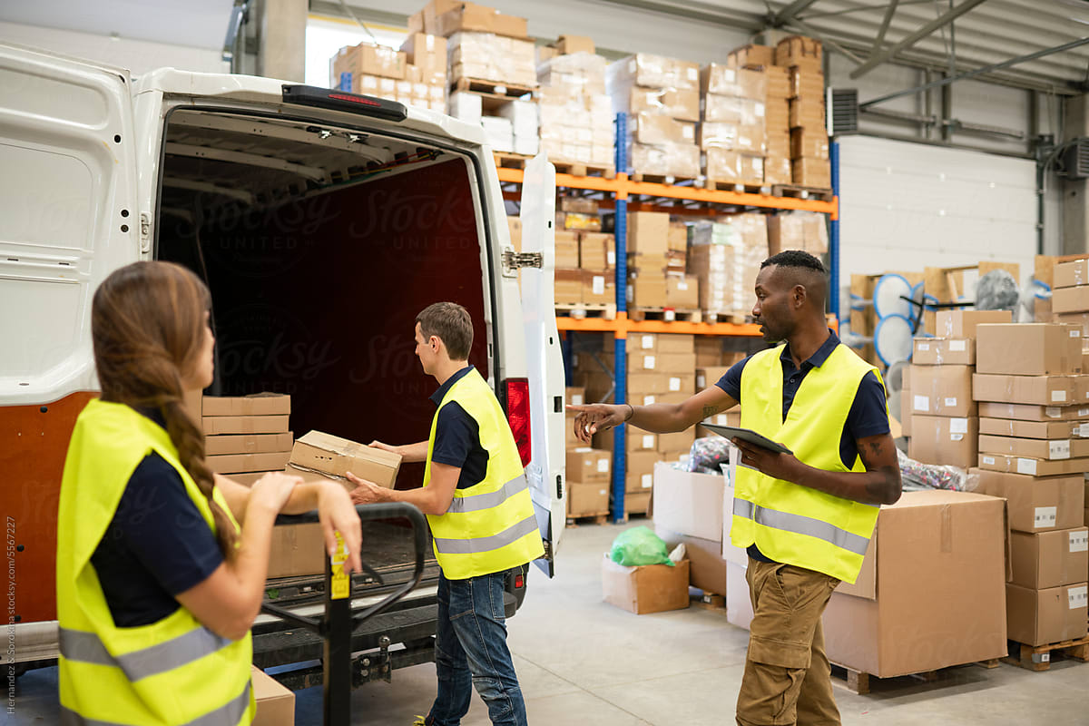 Workers Loading Delivery Van In The Warehouse