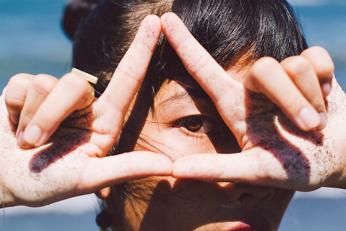 Woman\'s eye looking through the triangle hands sign