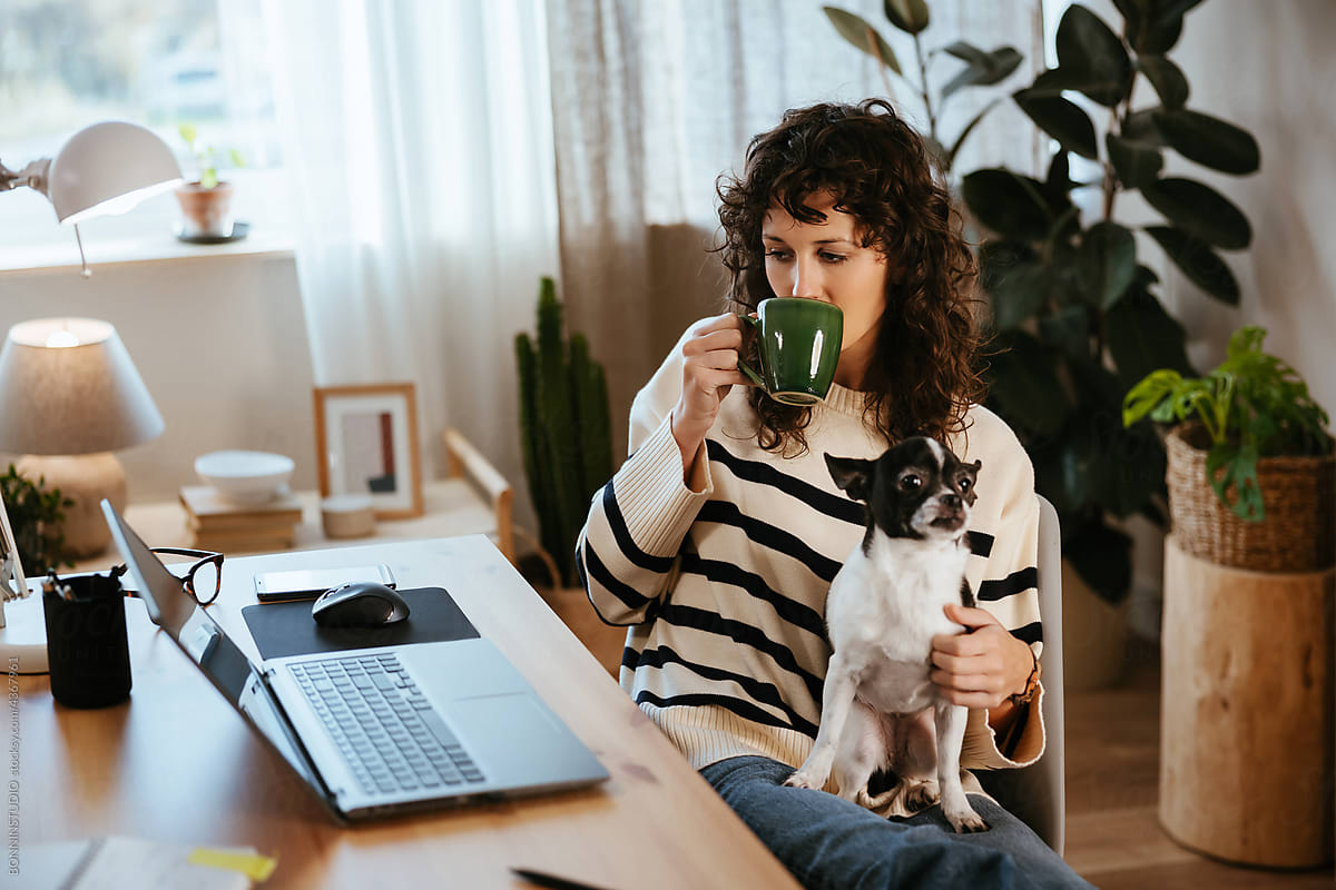 Female freelancer with dog drinking hot beverage