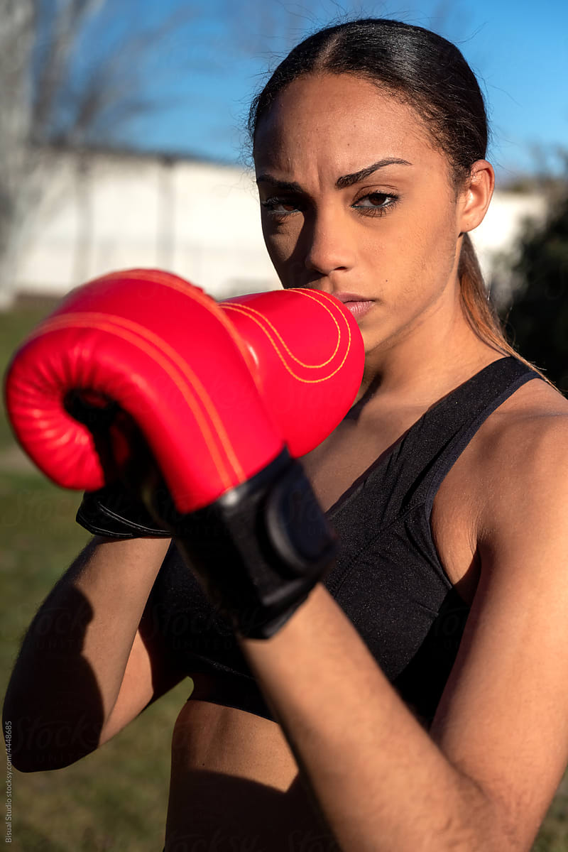 Serious female boxer in gloves in park