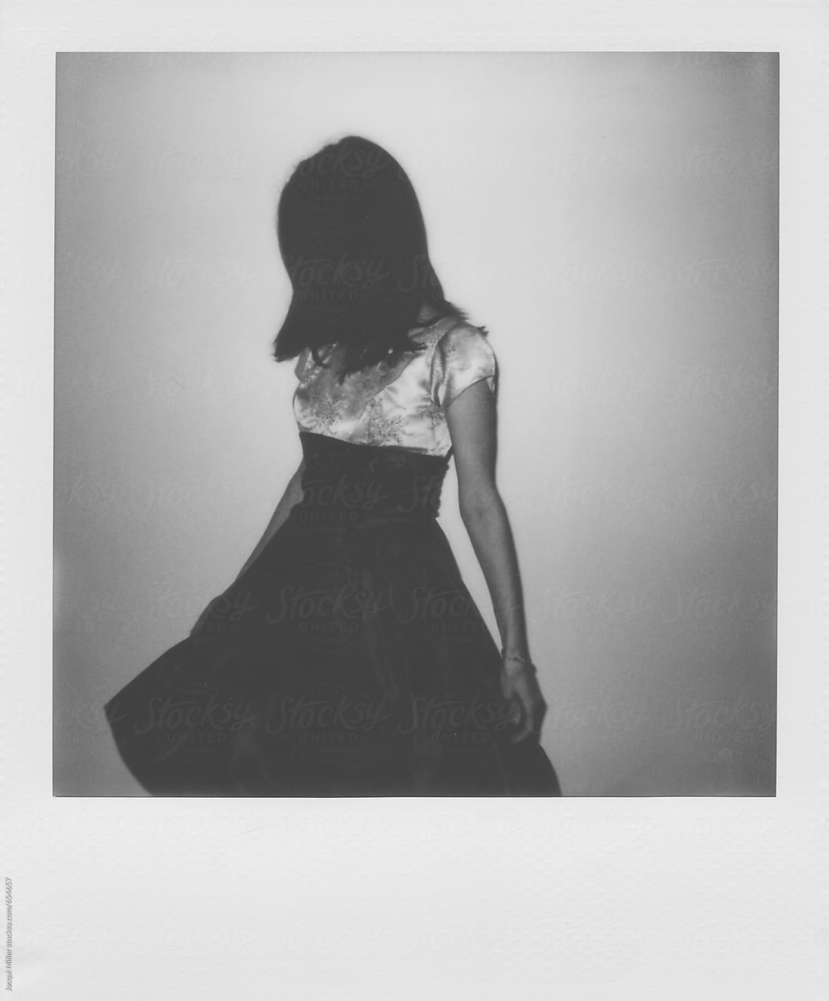 Black and white polaroid of unrecognisable woman wearing a vintage dress and dancing