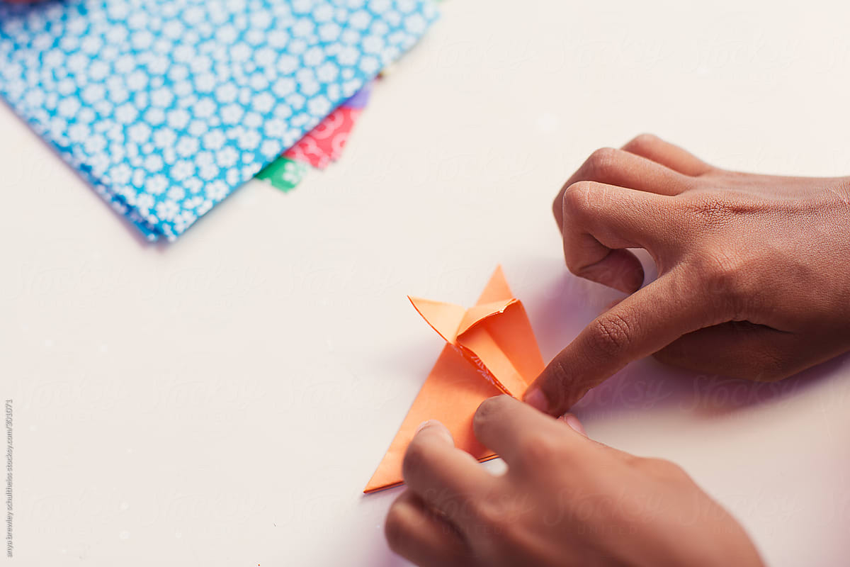 Child folding paper to make an origami fox.