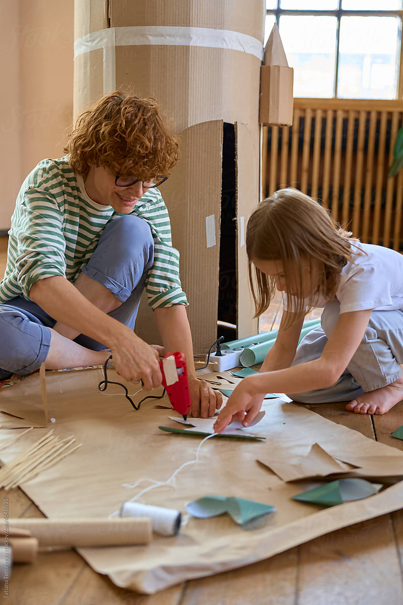mom and child glue paper flags for cardboard house
