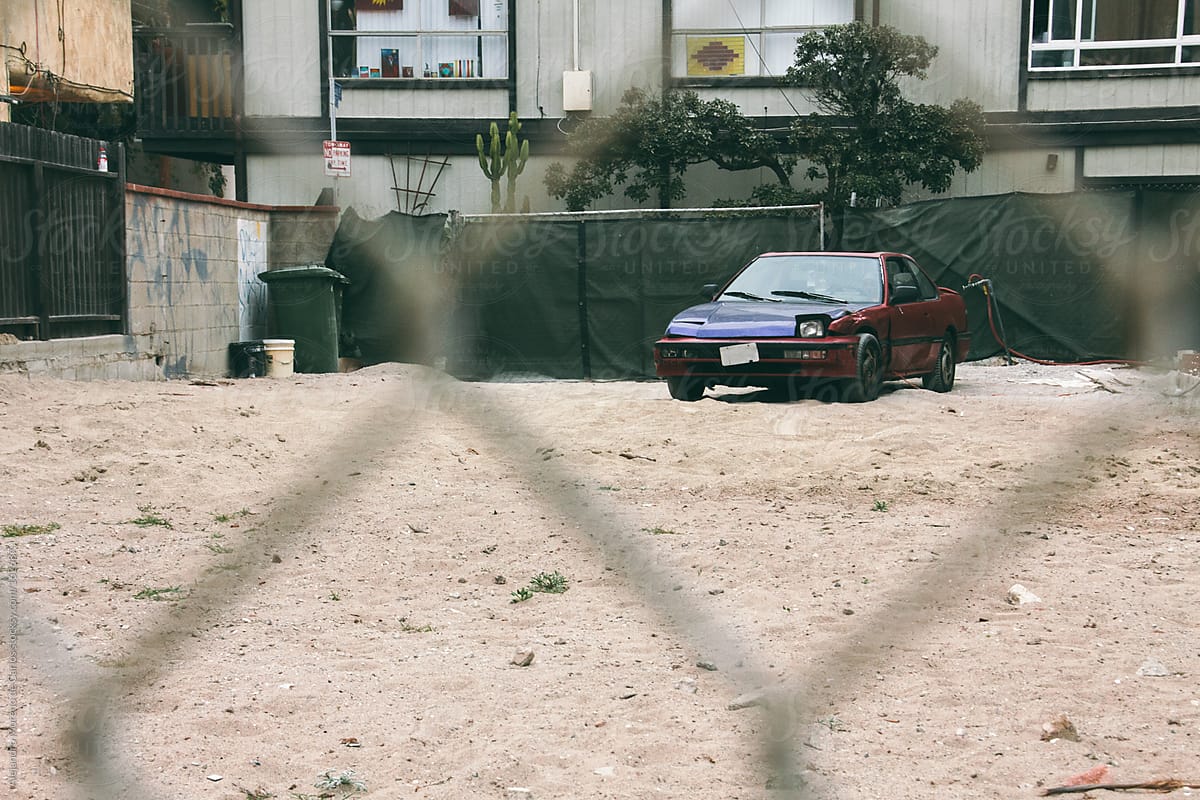 Old vintage car on sand parking seen through a fence