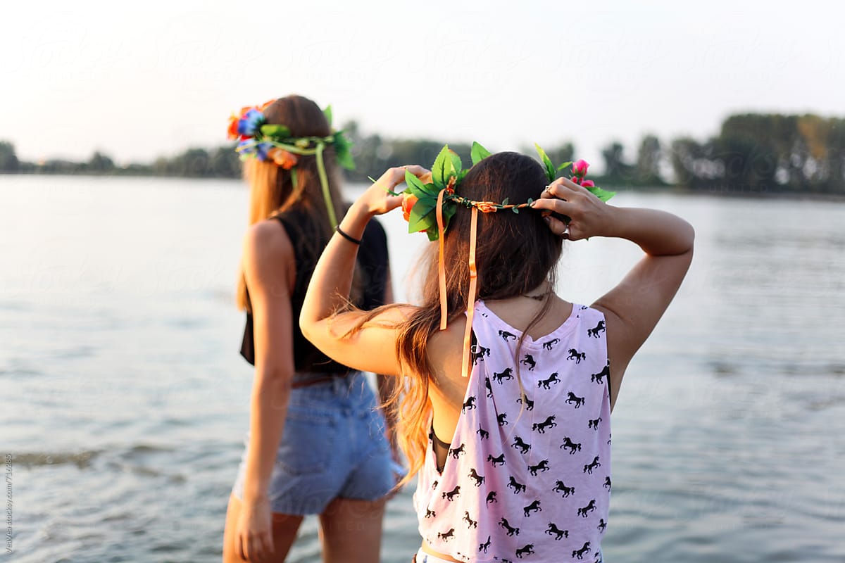 Two girls with flower wreaths in the river from the back