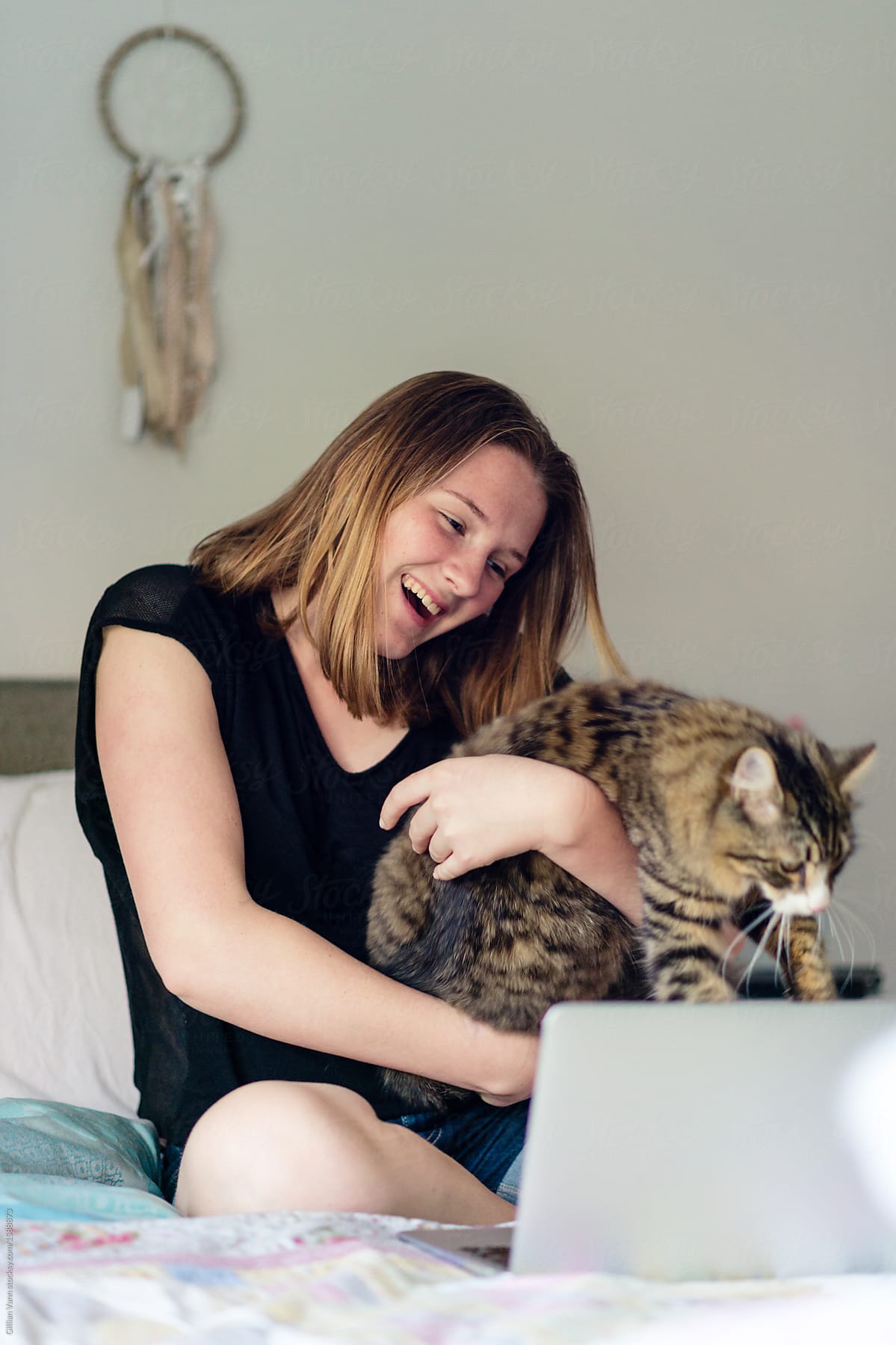 teenager in her room with laptop and cat
