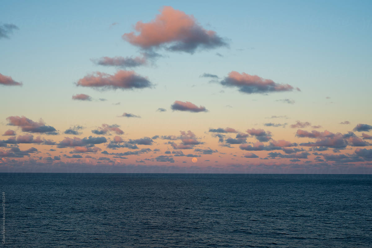 the ocean at sunset, with the moon rising