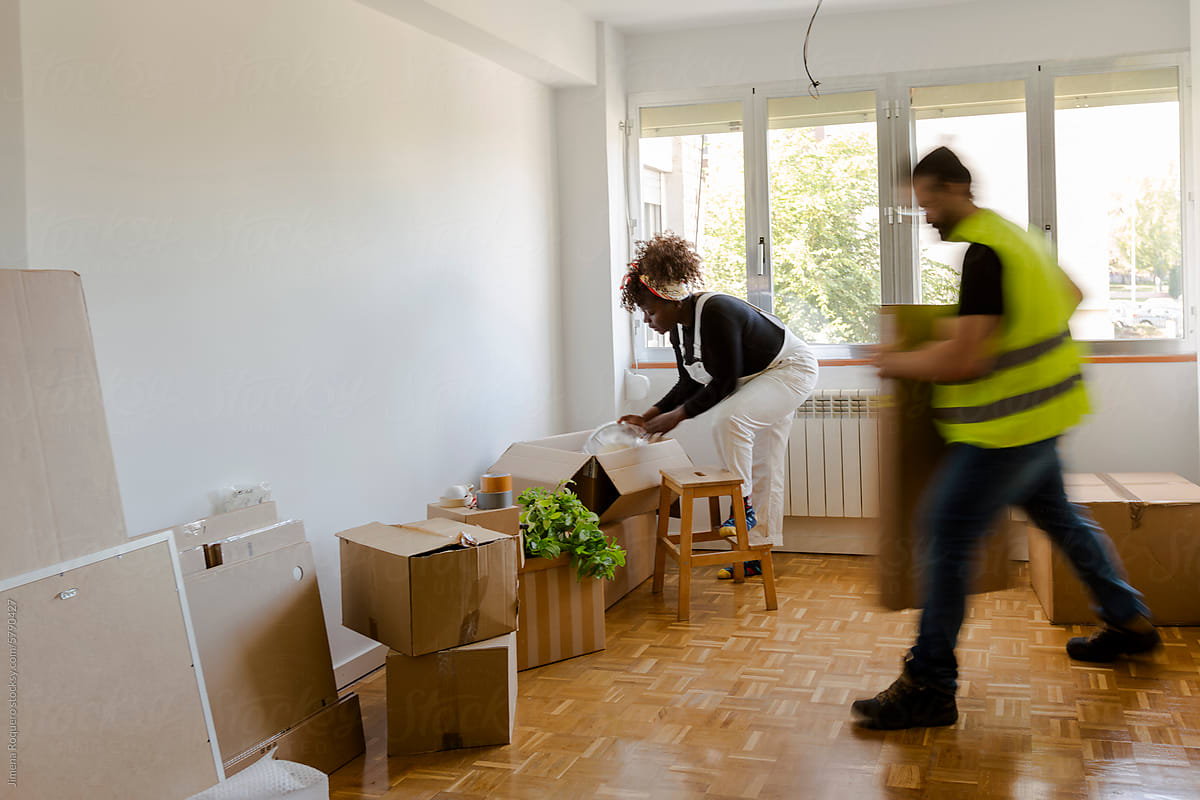 Moving staff moving in boxes to new home while owner unpack