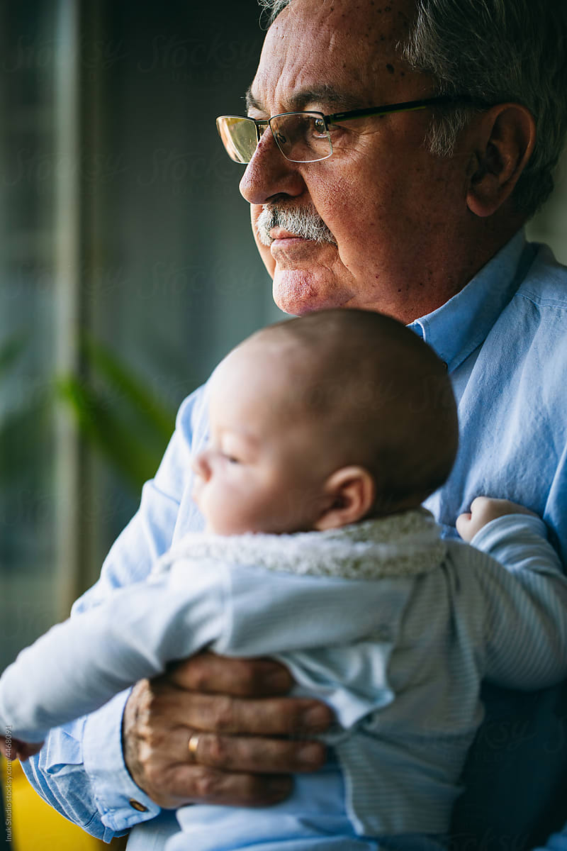 Loving grandfather holding newborn baby in arms