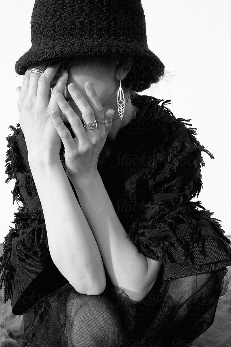 A woman in black hat closes her face