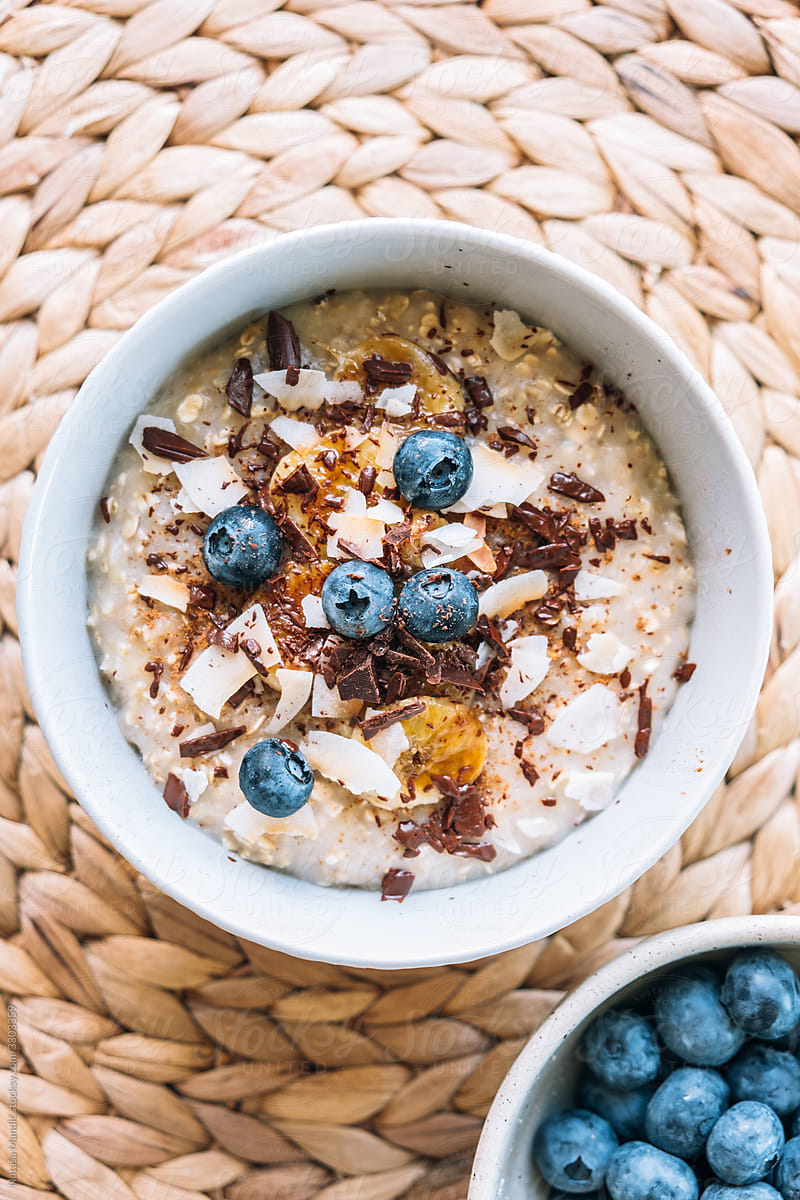 Porridge topped with caramelized banana, chocolate, shredded coconut and bluberries