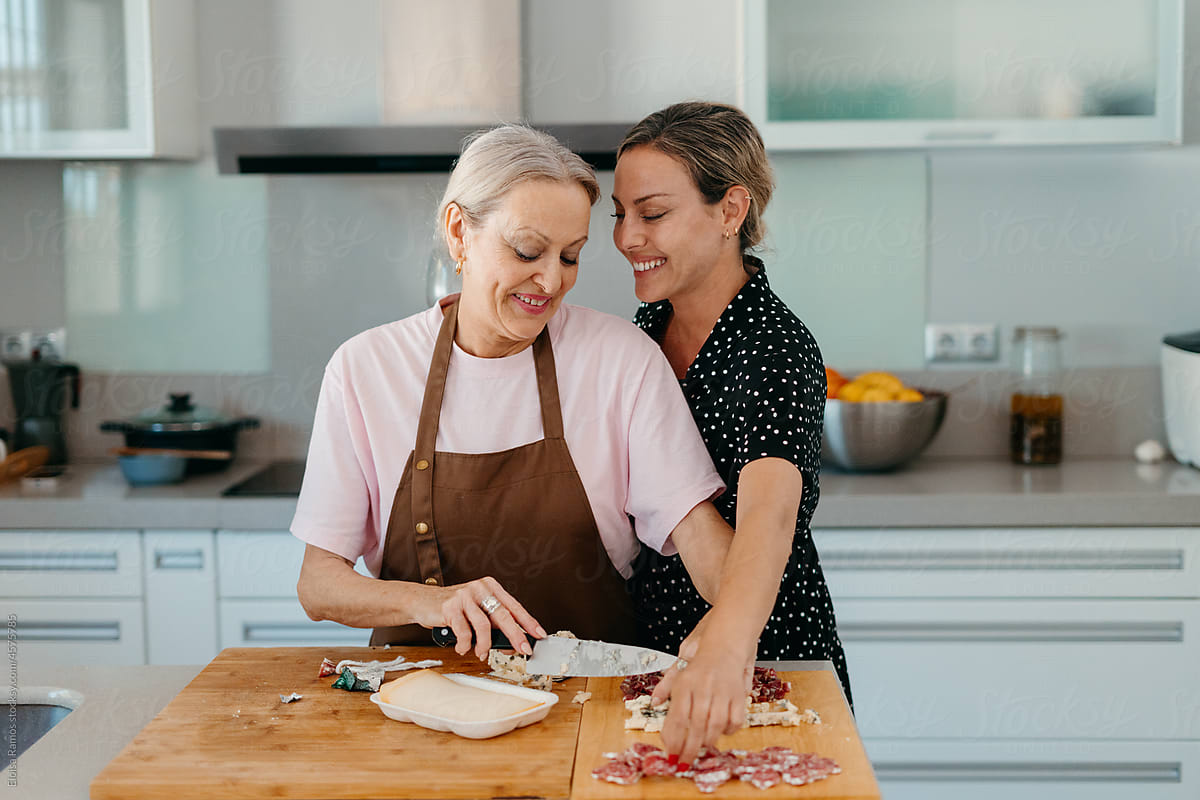 Senior mother and adult daughter preparing snacks in kitchen