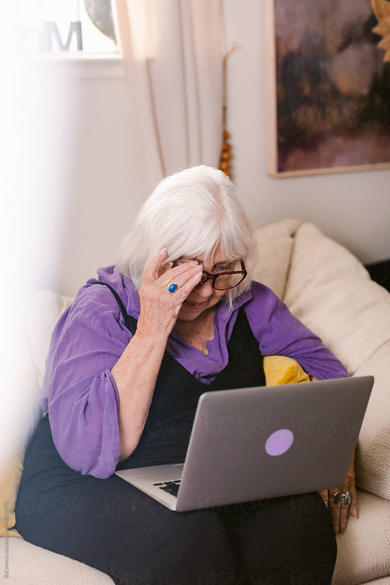 Senior lady using laptop on sofa at home