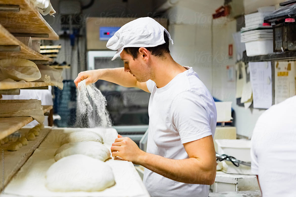 Baker Pouring Flour on Raw Bread Dough