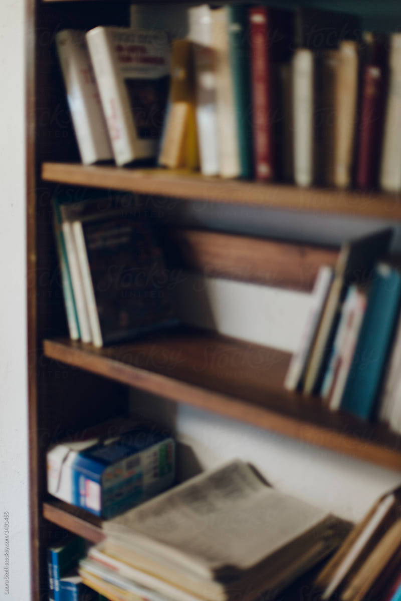 Blurry sight of books and newspapers on old wooden bookshelf