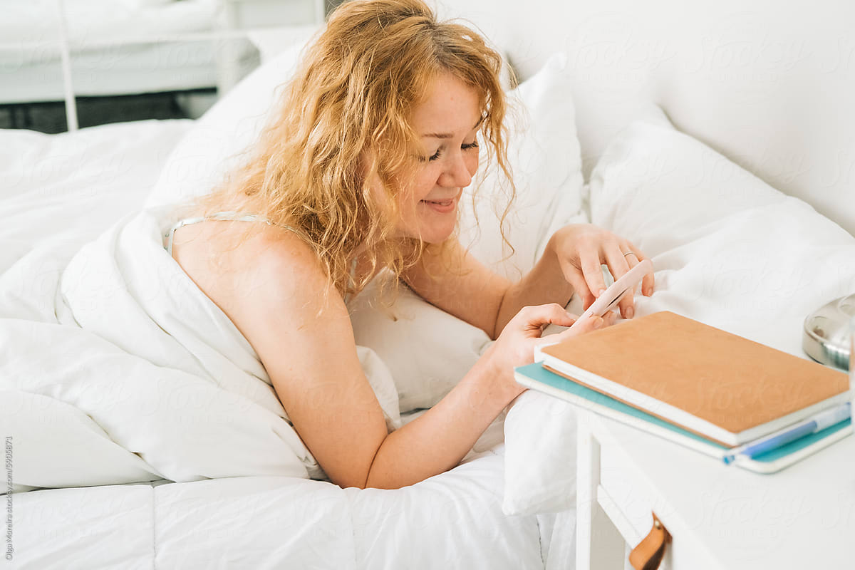 Woman interacting with her smartphone after waking up