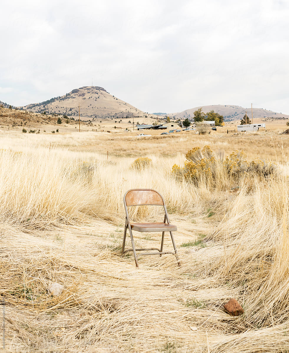 single chair empty in dry grass desert field environment.