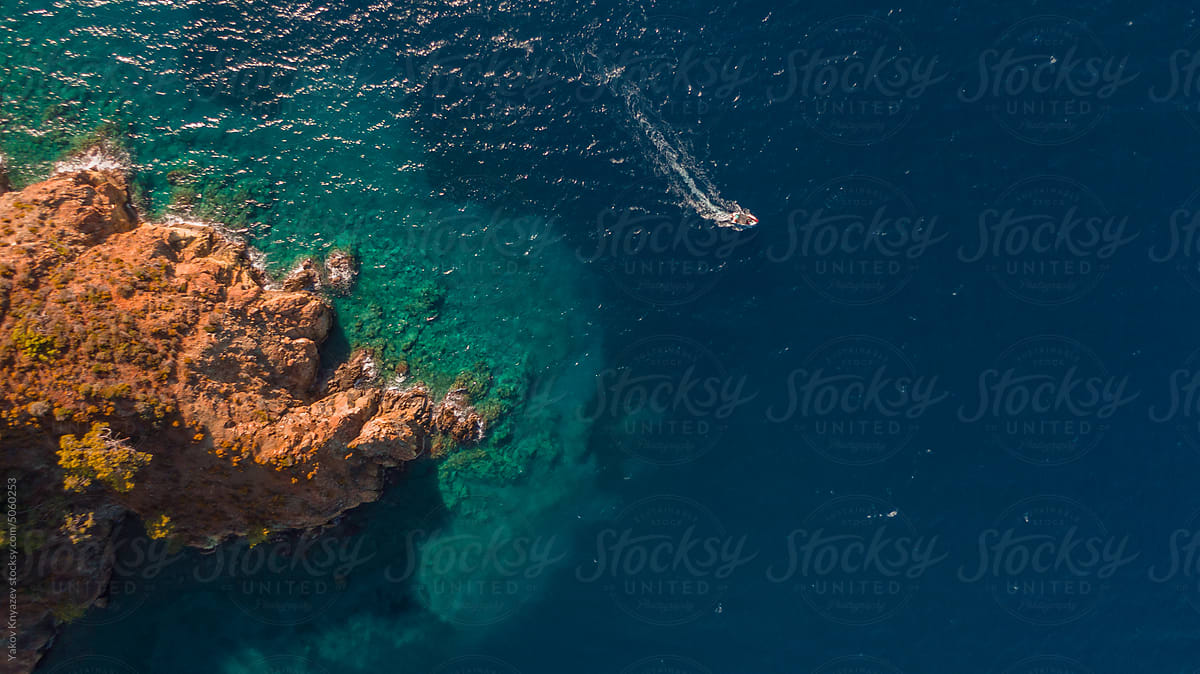aerial photo of boat speeding fast from the coast