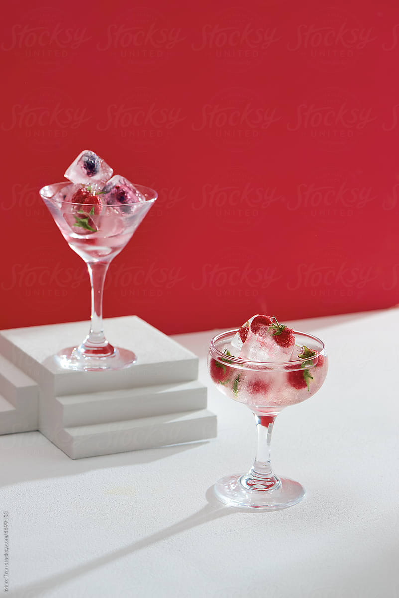 Martini and champagne glasses with berry cocktail drink with ice