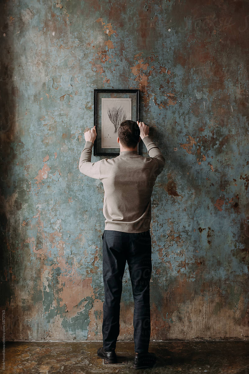 Man hanging painting on wall