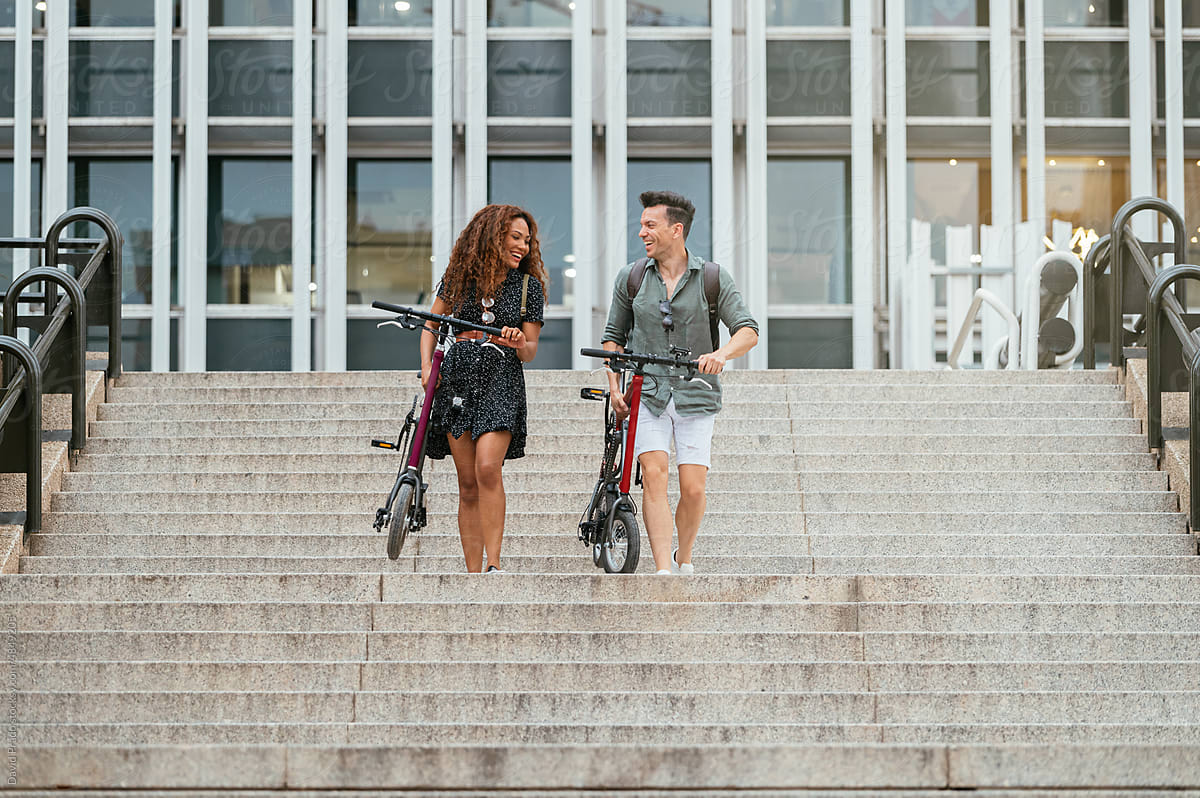 Cheerful coworkers bicycles walking on steps after work