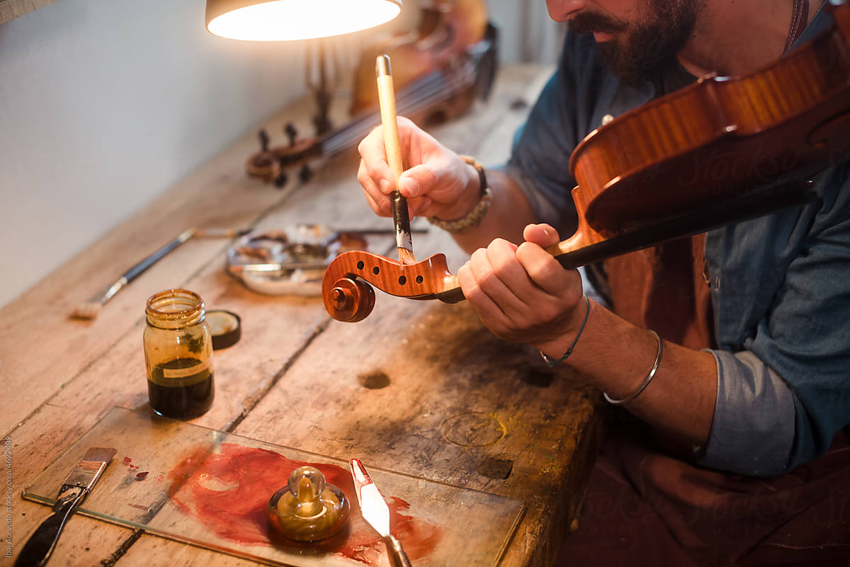 Artisan carefully varnishing a violin