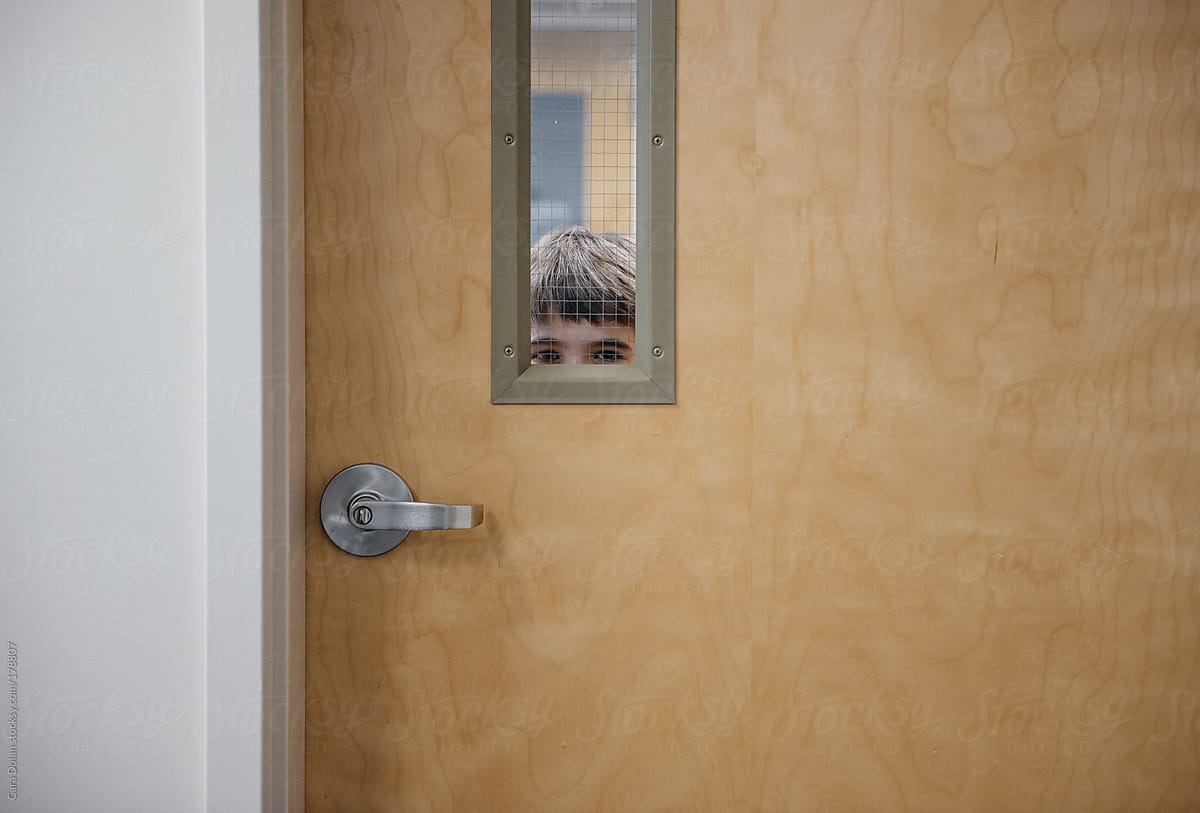 Boy peeks through a door at a school