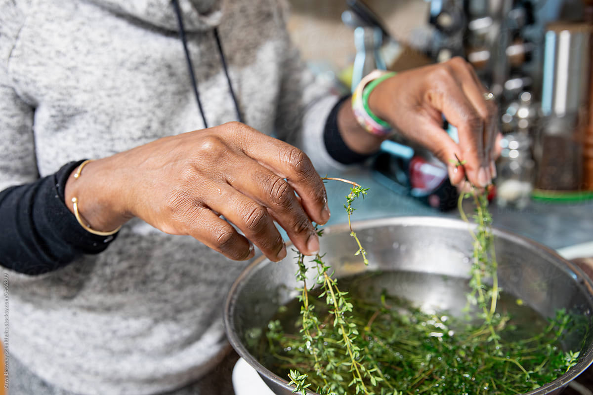 Closeup of the hands of a woman washing freshly picked thyme