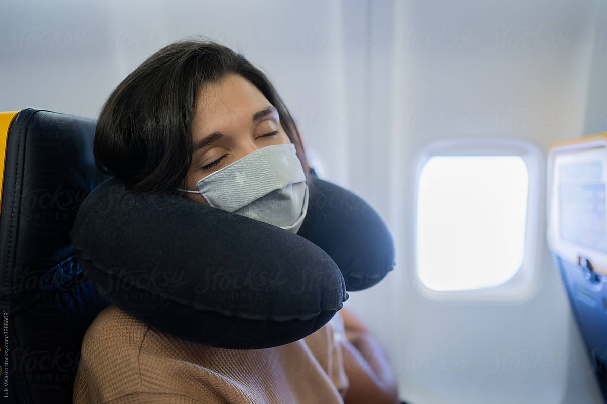 Woman With Mask Sleeping During A Commercial Flight.