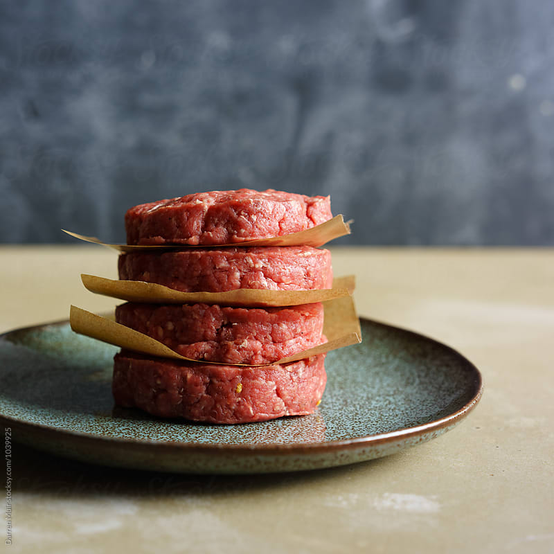 Four raw ground Aberdeen Angus beef patties on a plate.