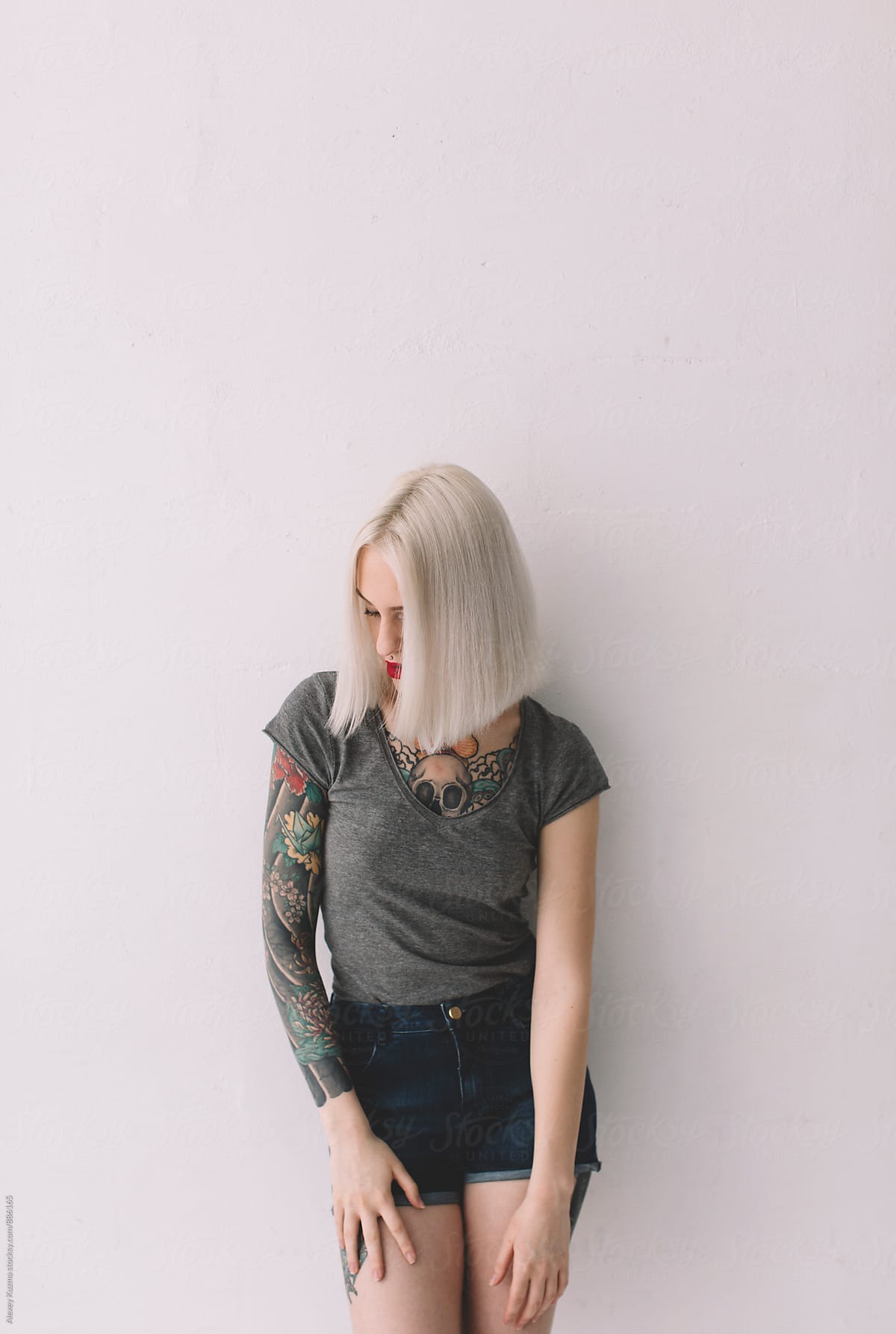 young blond woman with tattoos on the white background