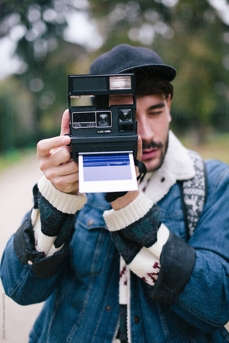 Young man takes pictures at the park with a instant camera