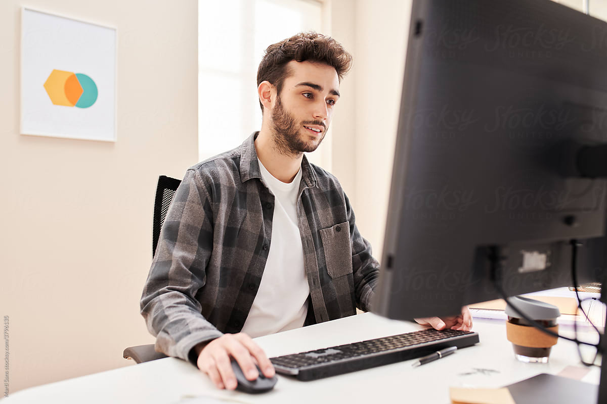 Glad young man browsing computer in home office