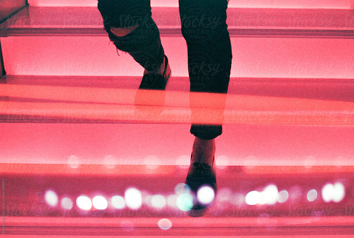 Silhouette of woman walking down a bright red, lit staircase at night