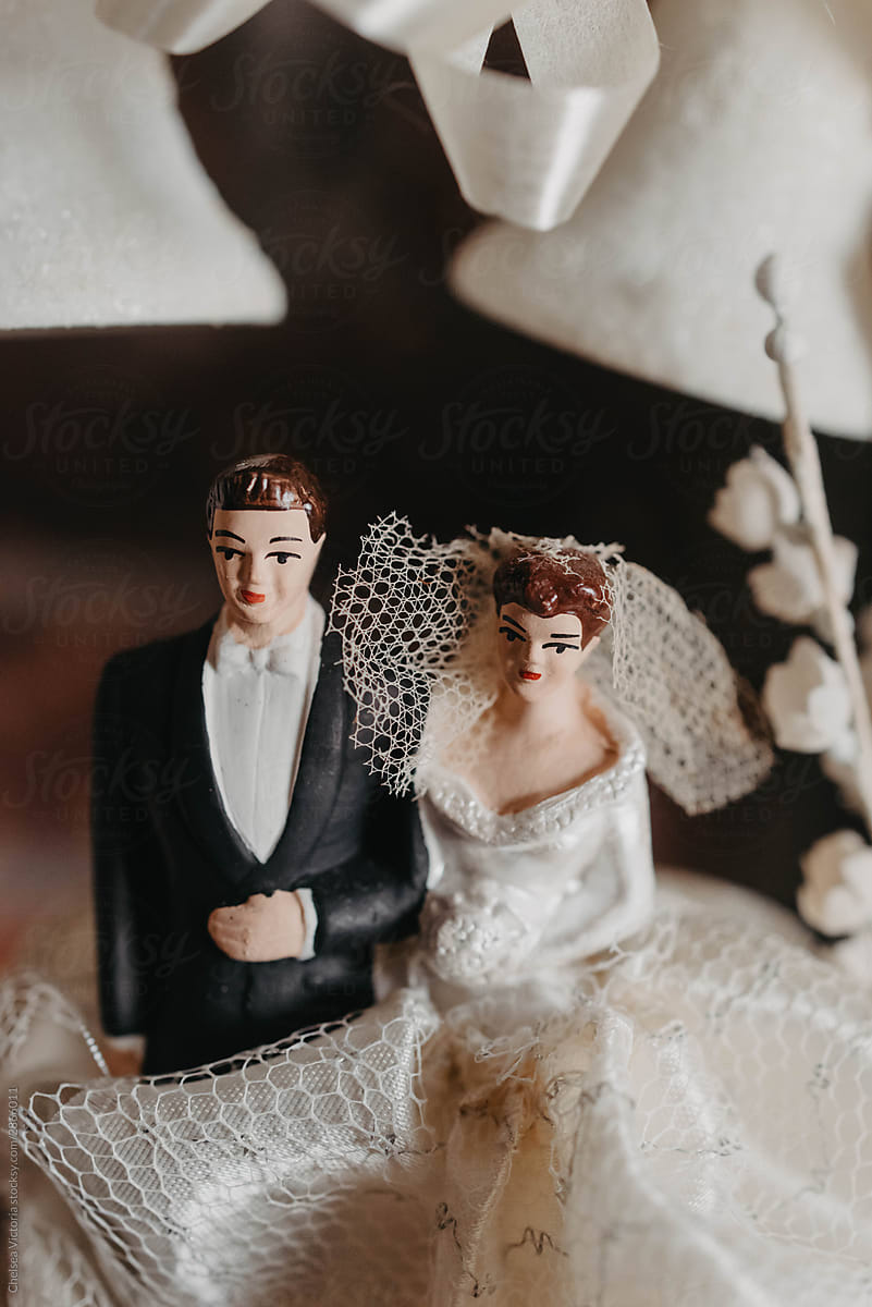A bride and groom on the top of an old fashioned wedding cake topper