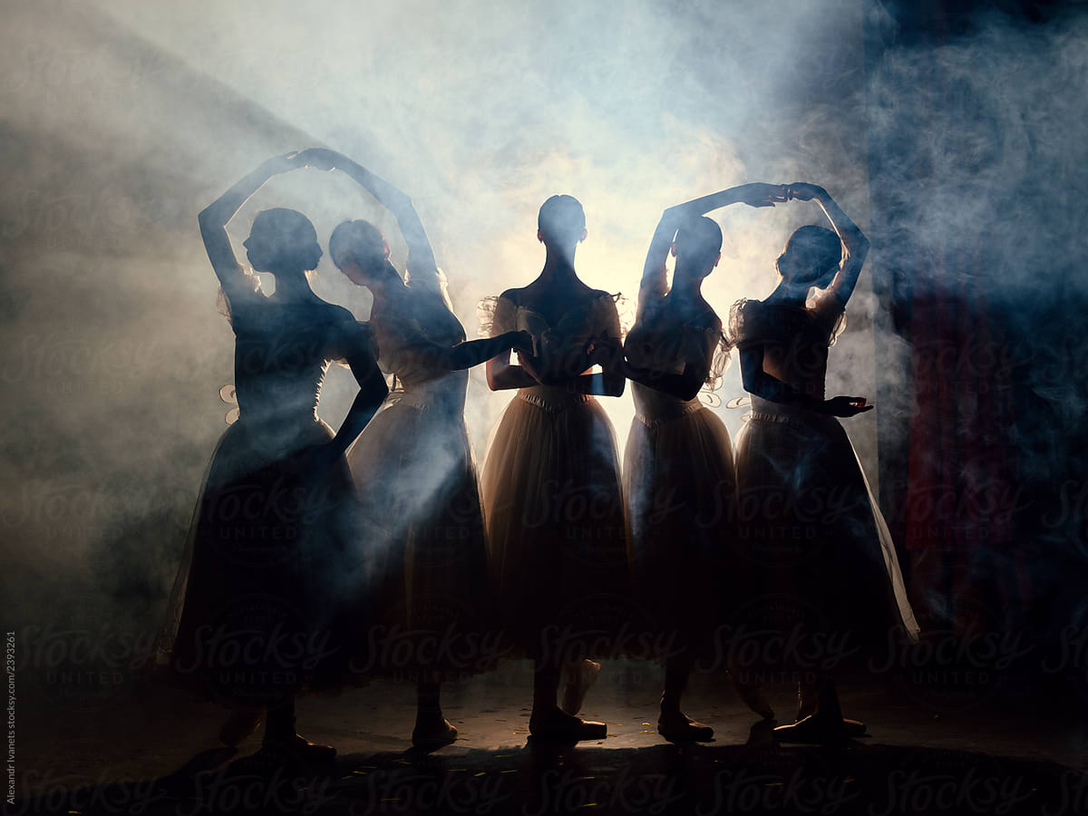 Ballerinas in dresses posing in darkness